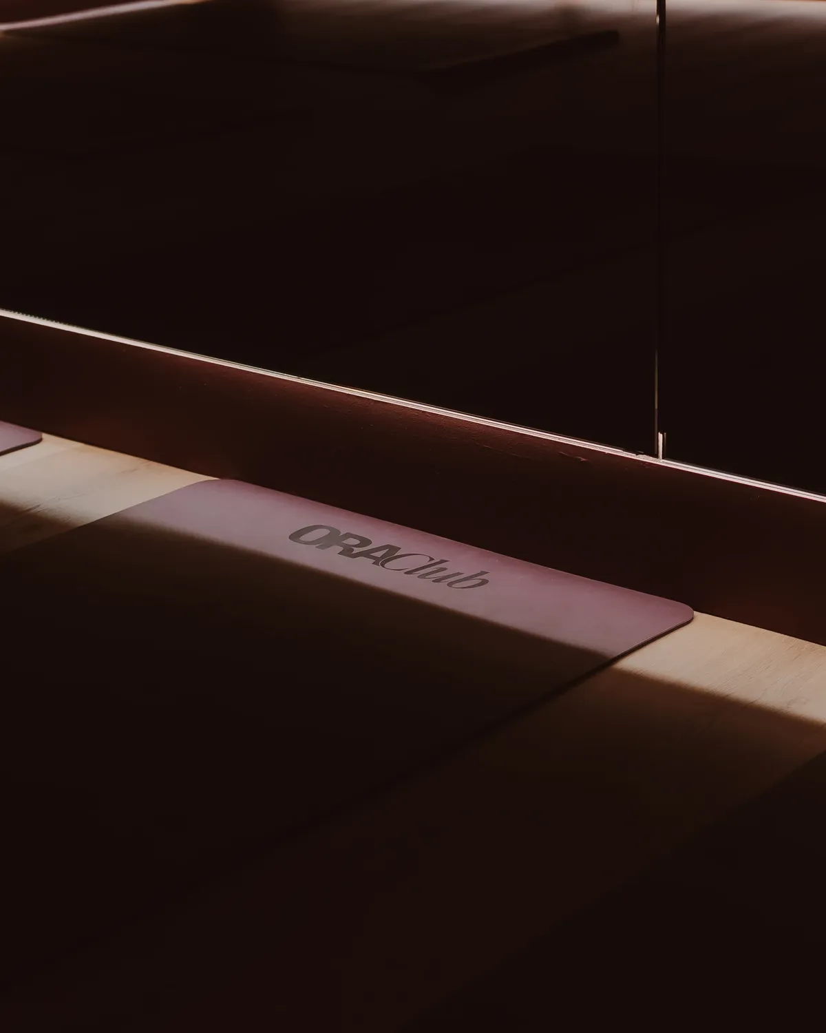 Tapis Ora Club déroulé sur le parquet, traversé par un rai de lumière